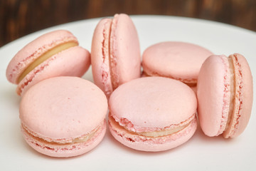 Pink macaroons on white stand on wooden background, homemade food