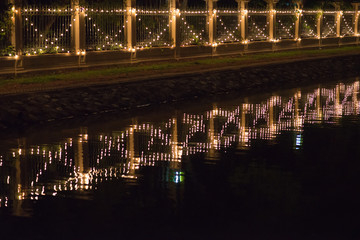 Decorated bulbs hanged on wall with reflection of canal at night