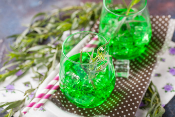 Drink from an estragon with ice in a glass on a table. Selective focus. Copy space