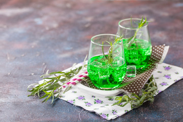 Drink from an estragon with ice in a glass on a table. Selective focus. Copy space