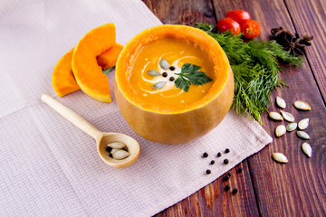 Traditional Cream soup in a pumpkin with lid Seeds spices dill and parsley