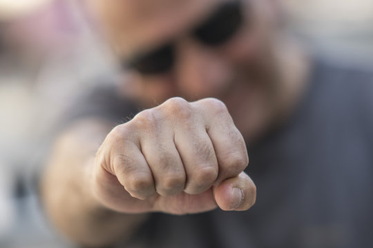 Man making clenched fist at camera. Selective focus