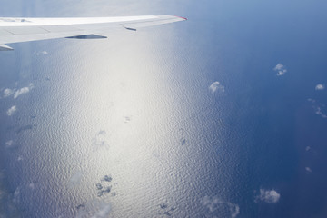 Aerial view of airplane wing over blue tropical ocean