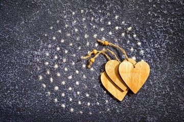 Dots of salt lined in a circle on a dark blue cement background and three wooden hearts with copy space as a food background