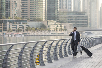 businessman on a phone, walking with his suitcase in Dubai Marina