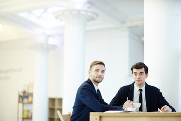 Successful brokers looking at camera while having meeting