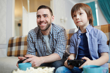 Man and his son with controllers enjoying video-game