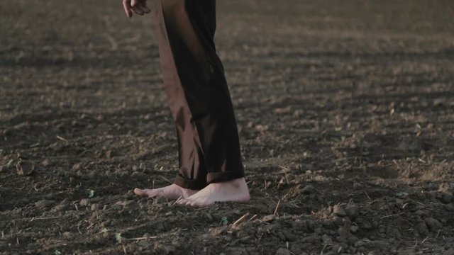 Male feet walking on the field barefoot. A man walks barefoot across the field, parts of the body (legs).