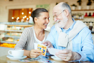 Senior couple looking through photos in cafe