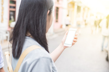 Young Asian traveling blogger or backpacker using route application on the mobile phone  to find the needed address in a city phuket, Thailand.