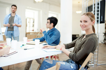 Obraz premium Pretty young designer making notes in notepad in working environment