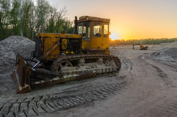 An old tractor with a large bucket extracts sand in a quarry