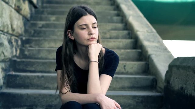 Pensive teenage girl sitting on stairs in city
