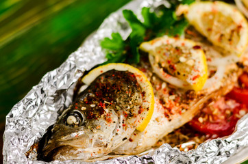 Fried fish in foil on a wooden background.