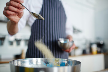 Baker adding salt in bowl with ingredients
