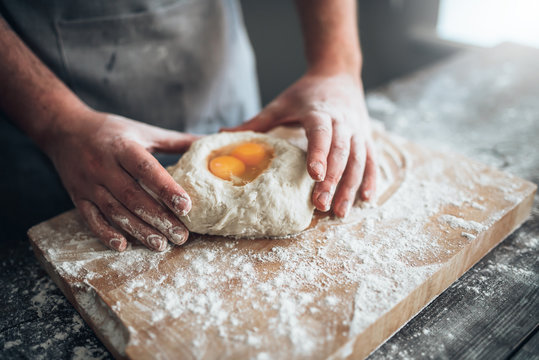 Male baker hands mix the dough with egg