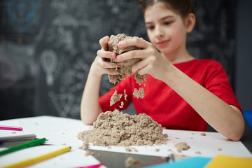 Portrait of little girl playing with kinetic sand during art class in child development center