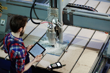 High angle shot of machine operator using cutter for glass in workshop