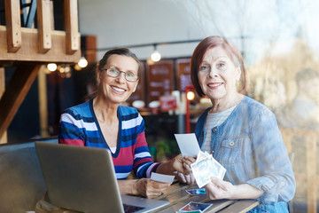 Smiling aged women with photos looking at camera