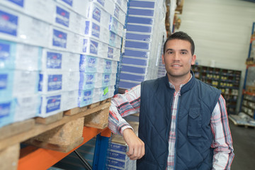 Portrait of man next to reams of paper in a warehouse