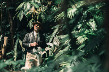 Alert explorer standing in jungle looking around.