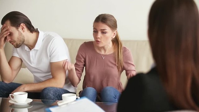 Family facing relationship difficulties. Young couple visiting professional marital therapist office, fighting with each other at therapy session. Woman yelling and complaining to marriage counselor