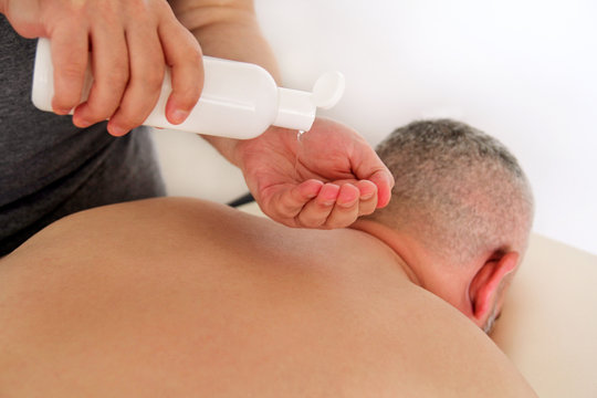 Massage relax studio. Men hands bottle massage oil. Body care. Man having massage in the spa body massage salon.