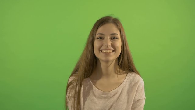 Portrait of a beautiful girl who smiles and laughs. On the background of a green screen.