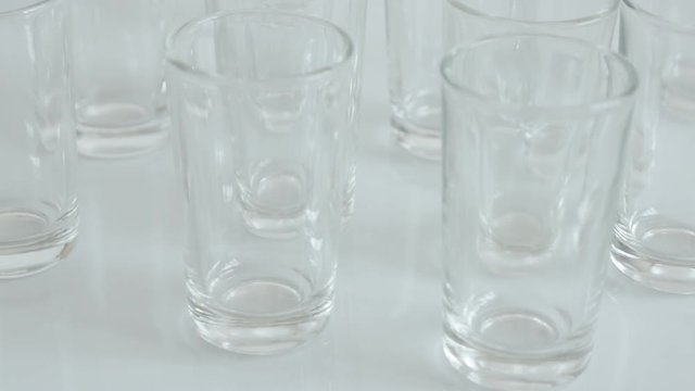 Tilting on shot glass pieces in bar on white background close-up 4K 2160p 30fps UltraHD footage - Slow tilt many spirits or liquor drink glasses 3840X2160 UHD video
