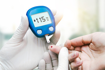 Doctor making blood sugar test. Hands with gloves on medical background