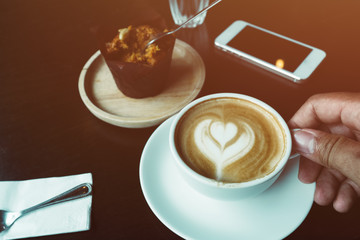 cup of coffee on old wooden desk. Simple workspace or coffee break in morning/ selective focus