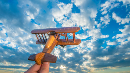 The hand launch wooden plane on the background of a blue sky © realstock1