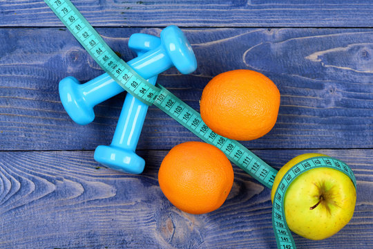 orange, apple, measuring tape and weight dumbbells for diet concept