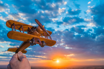 The hand launch toy plane on the background of a sunset