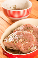 Selective focus on the marinated raw pork chops in the bowl.