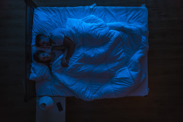 The couple sleeping on a bed. Evening night time. View from above