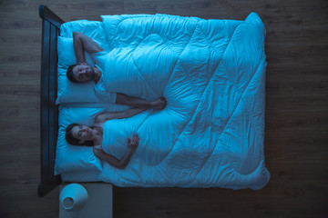 The young couple sleeping on the bed. night time. view from above
