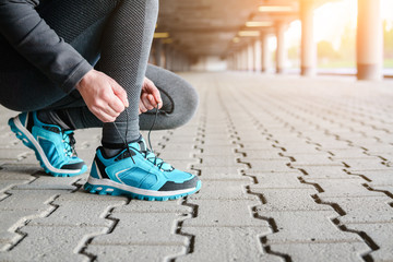 Female runner tying shoe lace in a urban area.