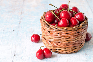 
 Fresh berries. Red ripe cherry in a round wicker basket on a light wooden background.