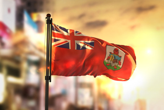 Bermuda Flag Against City Blurred Background At Sunrise Backlight