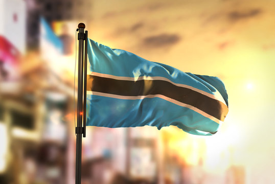Botswana Flag Against City Blurred Background At Sunrise Backlight