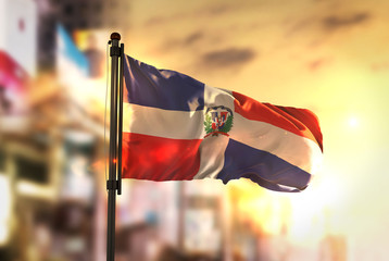 Dominican Republic Flag Against City Blurred Background At Sunrise Backlight - obrazy, fototapety, plakaty