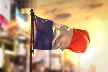 France Flag Against City Blurred Background At Sunrise Backlight