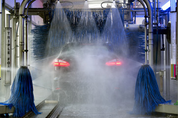 Waschanlage mit hineinfahrendem Auto und Gischt
