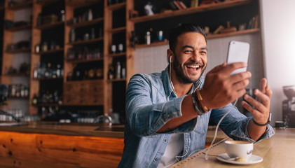 Man at coffee shop having a videochat on smart phone