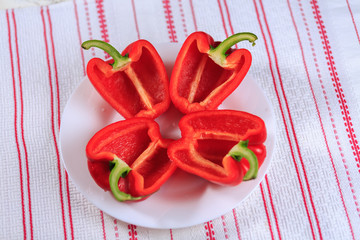 The crude red pepper cut in half on a plate on a white background