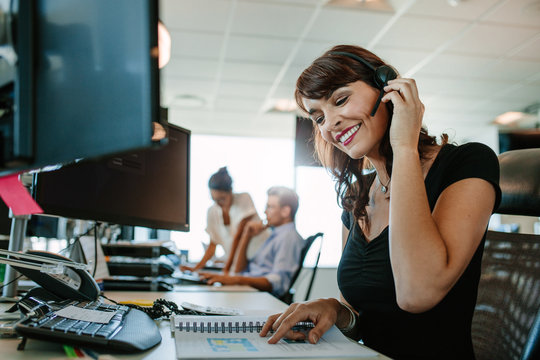 Smiling business woman with headset working at her desk