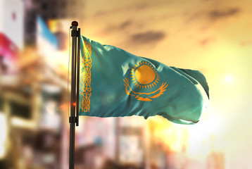 Kazakhstan Flag Against City Blurred Background At Sunrise Backlight