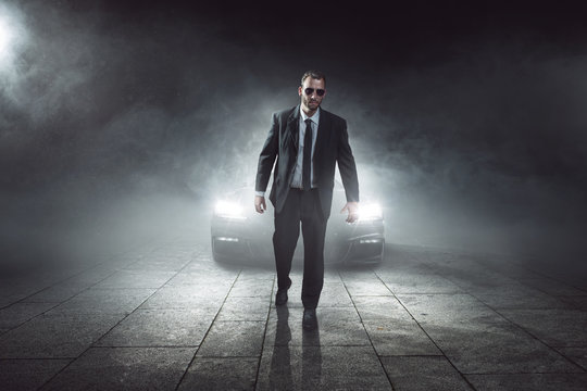 Mann im Anzug vor einem Auto in Dunkelheit