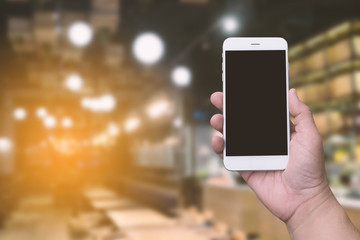 hand holding blank screen smartphone with blurred background restaurant or coffee shop for technology 4.0; internet of thing; payment concept.